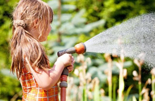 Kind mit Gartenschlauch